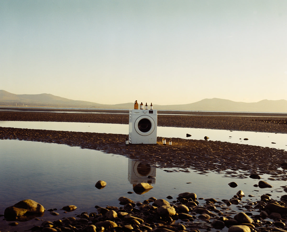 Attirecare bottles and a washing machine on the peaceful Anglesey shoreline at sunset